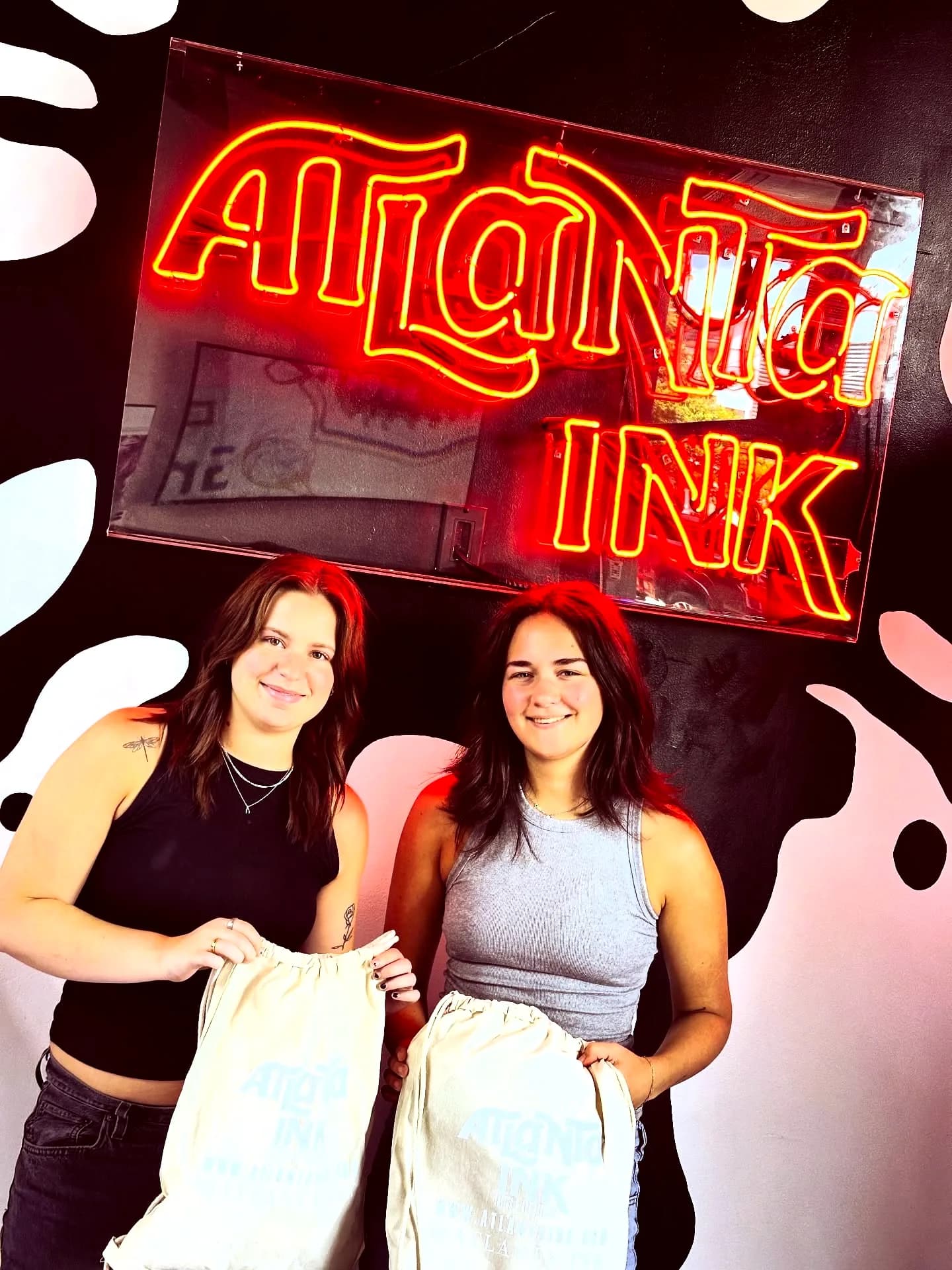 Two clients with ATLANTA INK bags under the red neon sign