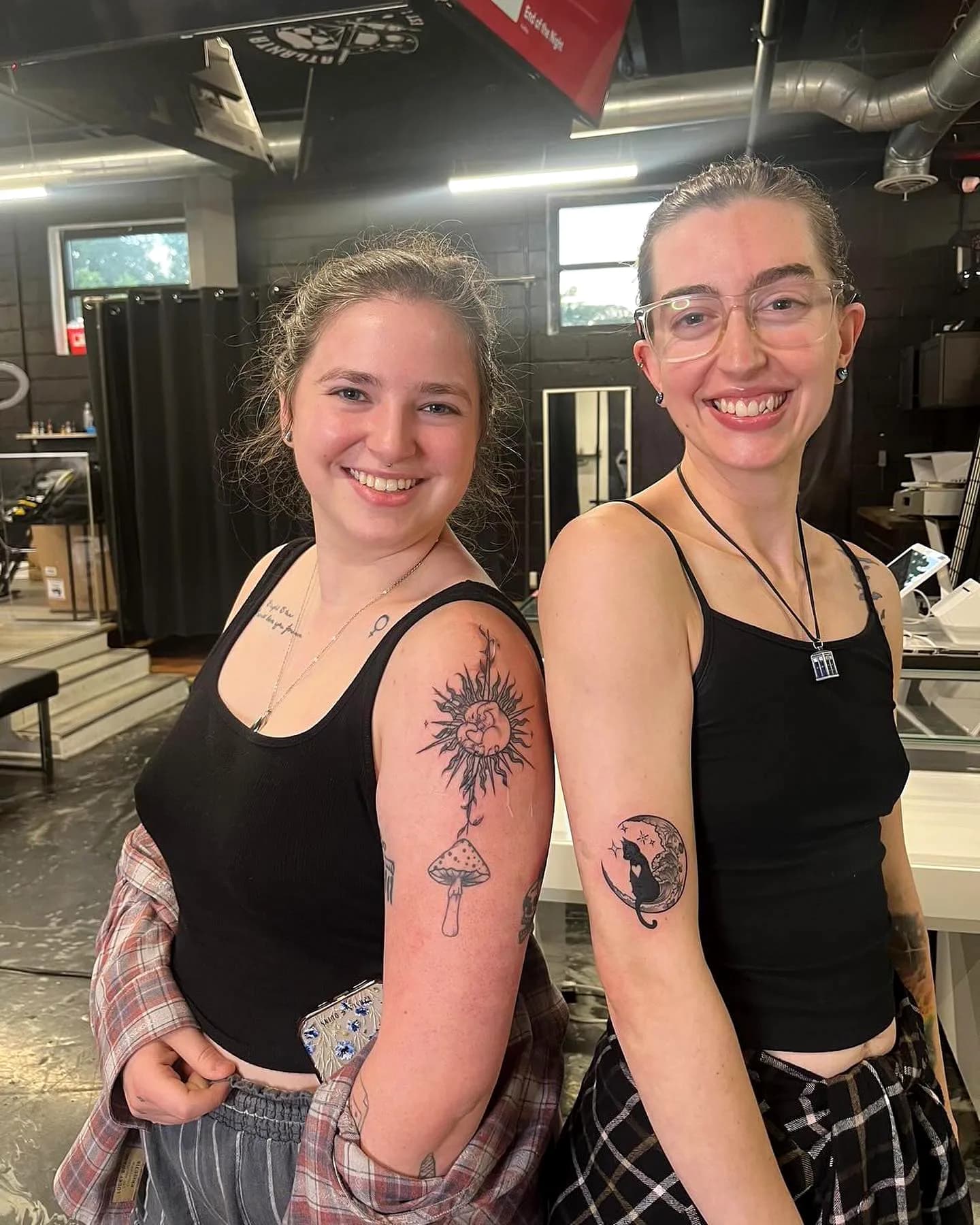 Two clients showing their new arm tattoos on the studio floor
