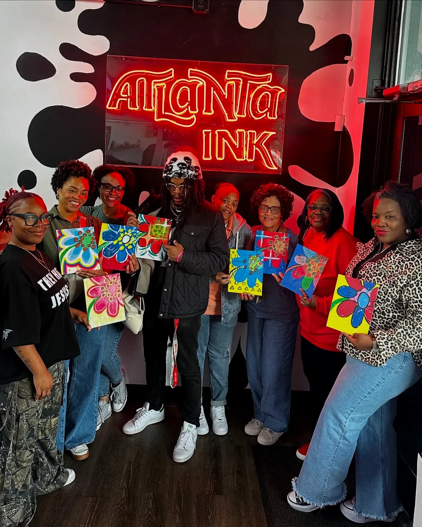 Group of guests holding painted artwork at an ATLANTA INK event