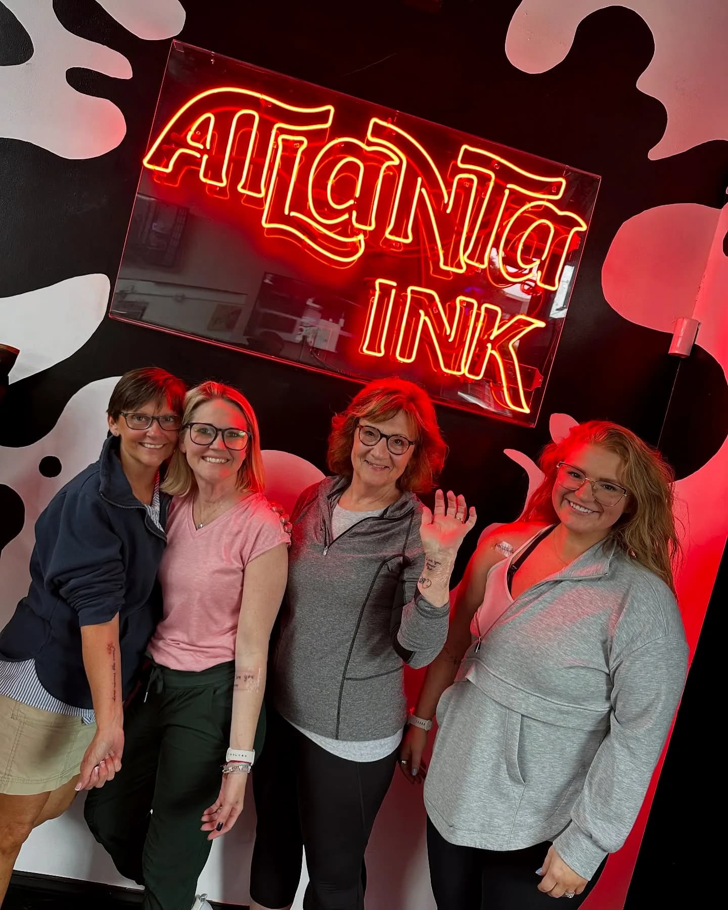 Group of staff and guests posing under the red ATLANTA INK neon sign