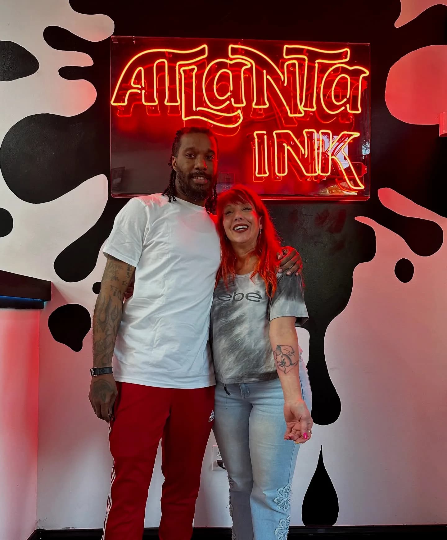 Two guests posing together under the ATLANTA INK neon sign