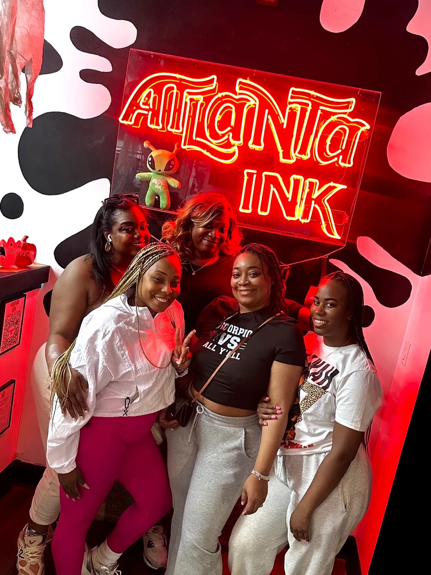 Group of guests posing under the ATLANTA INK neon sign