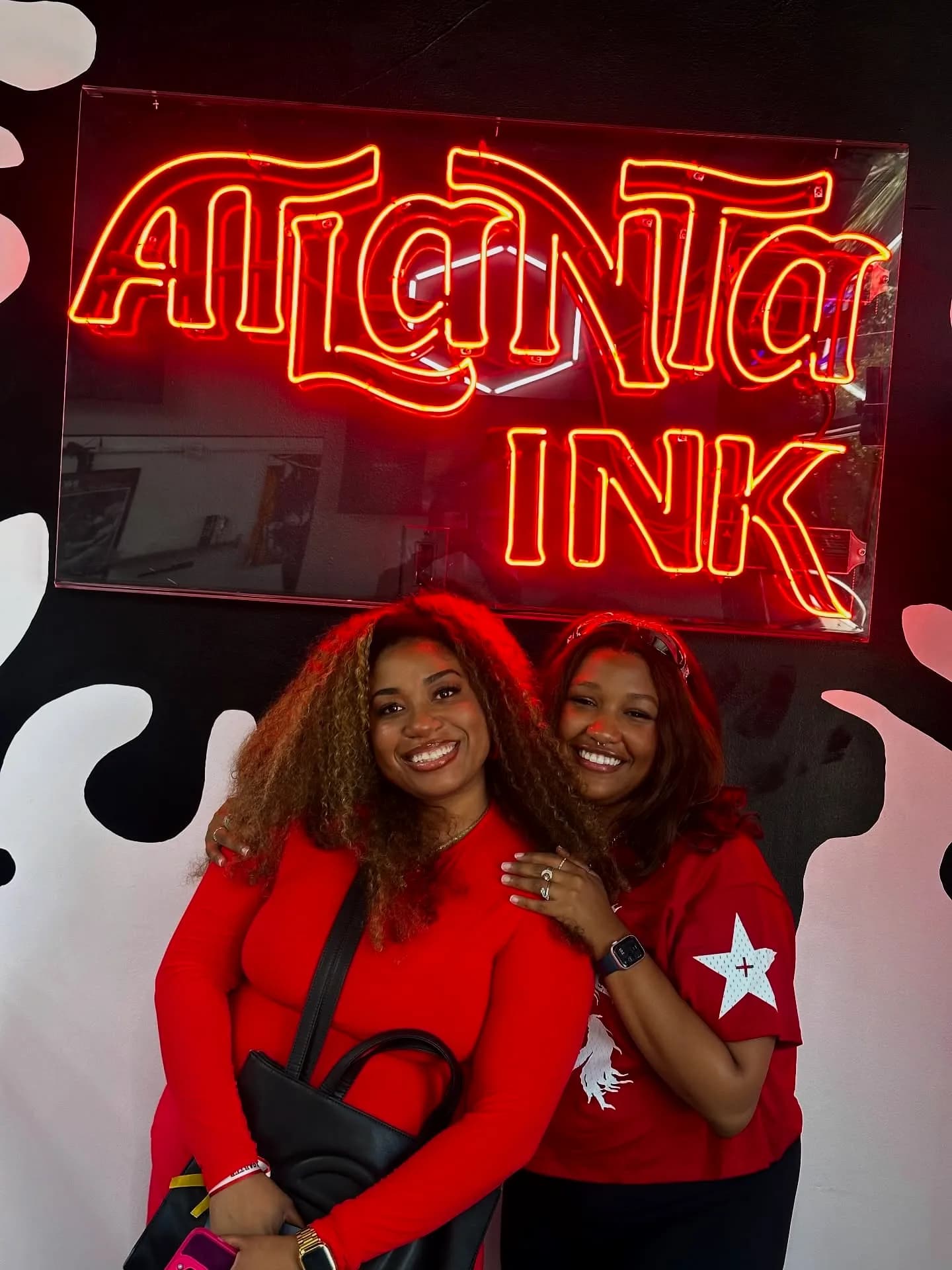 Two guests posing under the ATLANTA INK neon sign