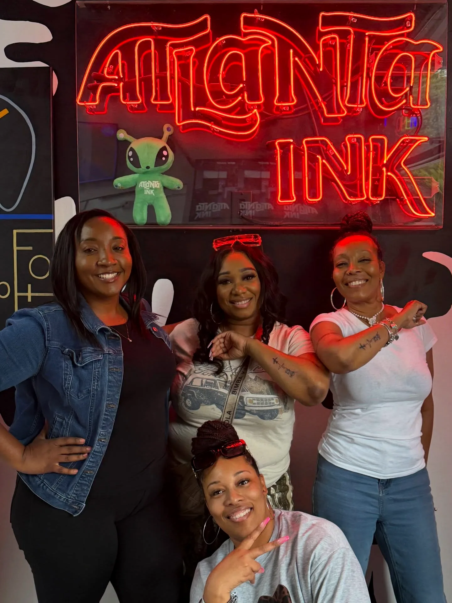 Group of guests posing under the ATLANTA INK neon sign