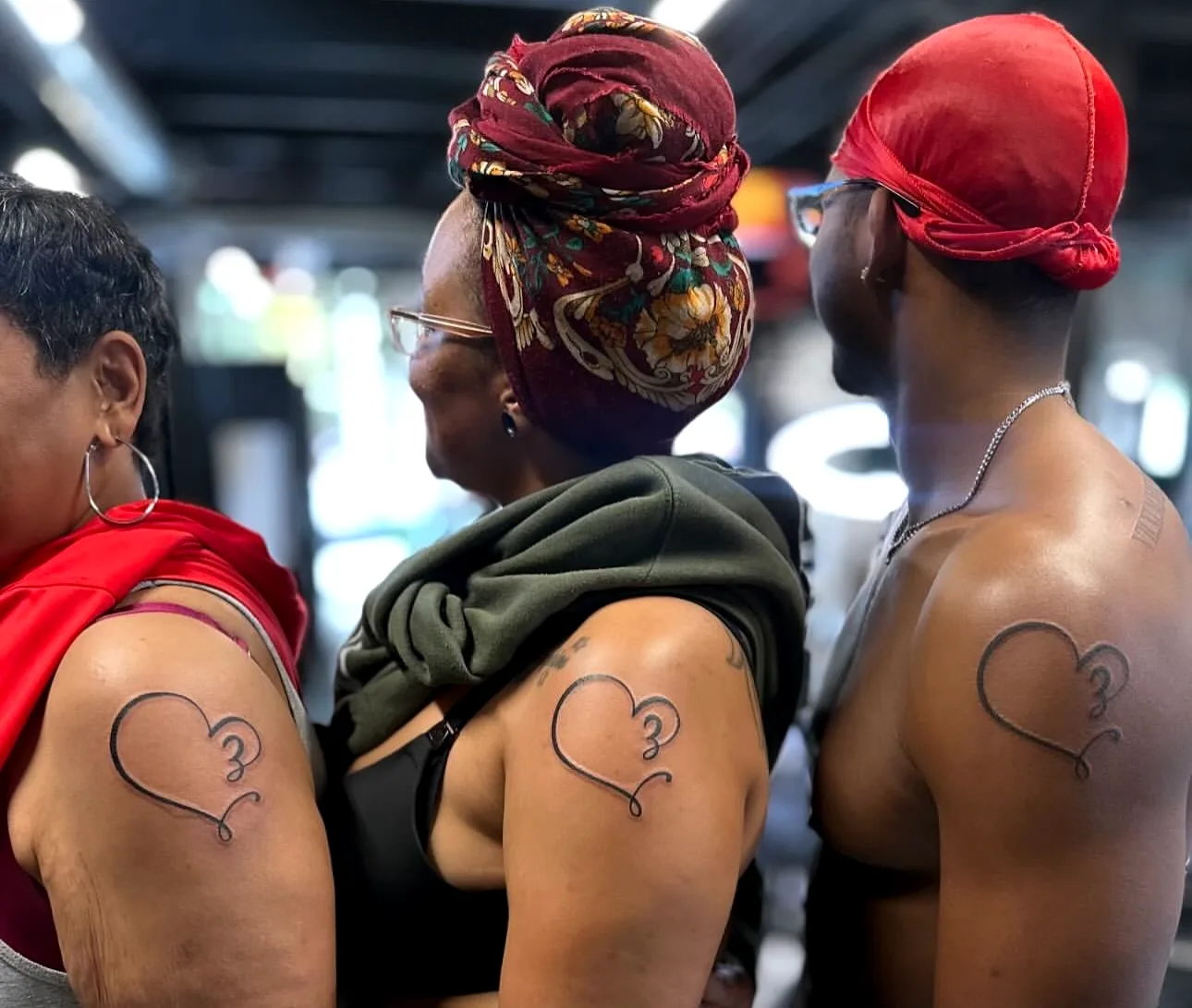 Two clients showing matching heart tattoos on their shoulders at ATLANTA INK
